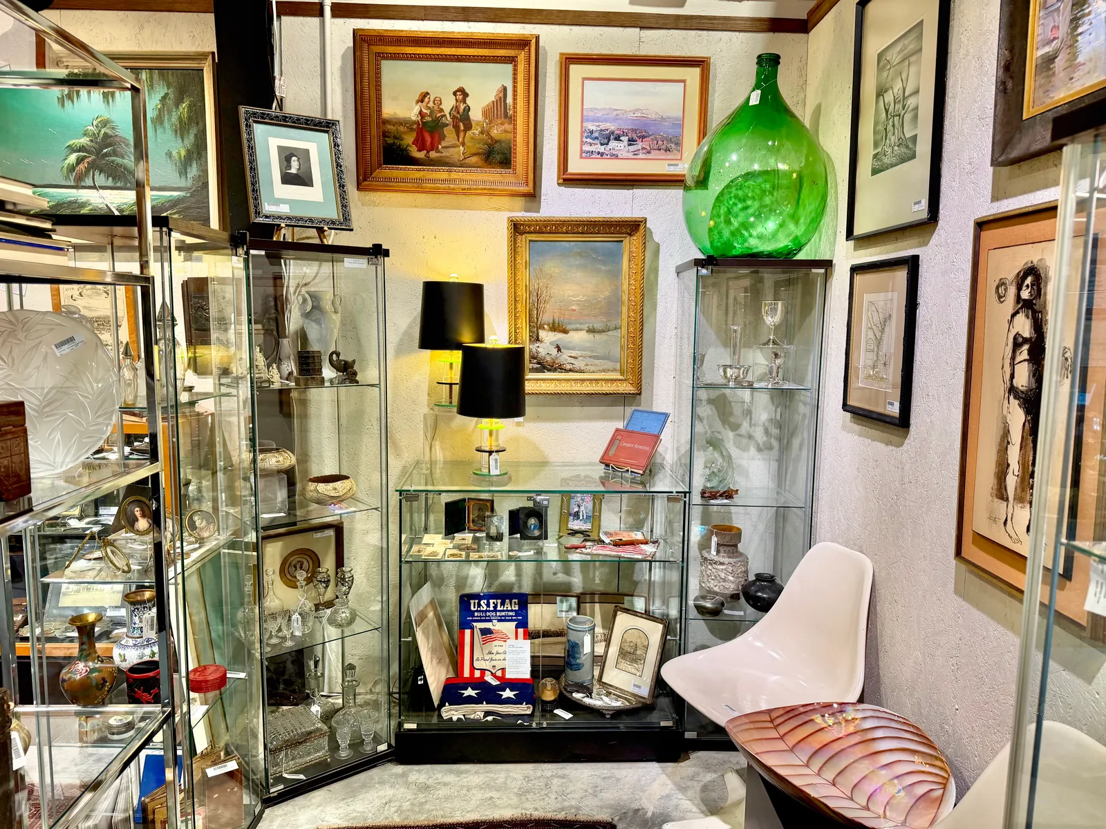 Glass display cabinets, framed paintings and a green glass vase